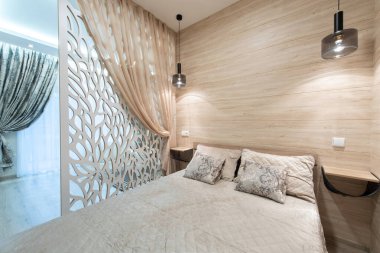 Doğal ahşap aksanları, yorgan örtülü yatak örtüsü ve ortam ışıkları olan şık ve sakin bir yatak odası, rahat ve davetkar bir atmosfer yaratıyor. Modern Minimalist Ev Yatak Odası İçi