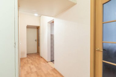 Parlatılmış ahşap döşeme, yumuşak nötr duvarlar ve konut ve ofis alanları için ideal fonksiyonel dekor elemanlarının yer aldığı basit bir koridor..