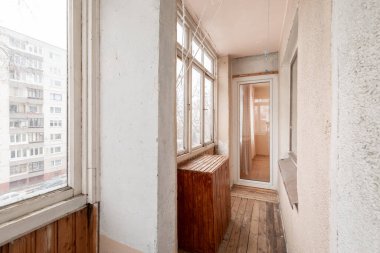 Geniş pencereli kapalı balkon manzaralı, ahşap panelli ve döşemeli, kentsel bir apartmanda yer alıyor. Eski Sovyet Tarzı Ev İçi