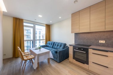 Rahat bir kanepe, yemek alanı, mutfak ve büyük pencereleri olan parlak ve rahat bir daire. Mutfak ve Mobilyalı Modern Daire Oturma Odası. Ev İçi