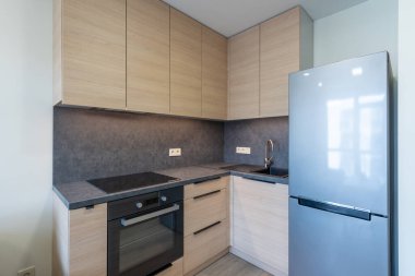 Çağdaş mutfak, ahşap dolap, dahili fırın, elektrikli fırın, ve zarif paslanmaz çelik buzdolabı. Kompakt evler için ideal. Ev İçi