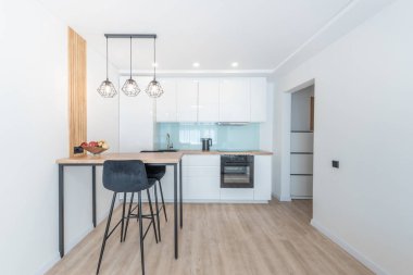 Ahşap tezgah, tabure ve asma ışıkları olan çağdaş mobilya tasarımlı parlak modern mutfak. Modern Minimalist İskandinav Mutfağı Parlak Parlak Mobilya Mobilyası