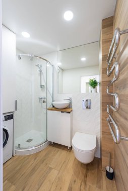 Küçük bir dizayn, ahşap döşeme, parlak eşyalar ve bir çamaşır makinesiyle tamamlanmış kavisli bir duş muhafazası. Ahşap döşemeli ve Minimalist Aletli Modern Ev Banyosu