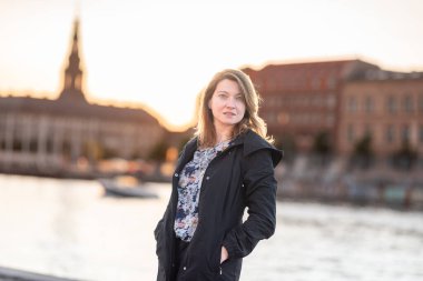 Sade bir günbatımı sahnesinde arka plandaki tarihi mimariye karşı siluet içinde duran bir kadın görülüyor. Kopenhag City, Danimarka 'da Yansıyan Kadın.