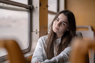 Kafkasyalı genç bir kadın trenin penceresinin yanında oturuyor, düşünceli bir ifadeyle başını elinin üzerine yaslıyor. Tren yolculuğu sırasında sakin ve içsel bir ruh halinde yakalanmış. Lizbon, Portekiz