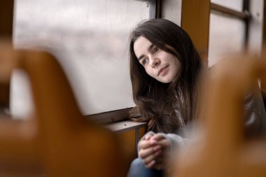 Kafkasyalı genç bir kadın trenin penceresinin yanında oturuyor, düşünceli bir ifadeyle başını elinin üzerine yaslıyor. Tren yolculuğu sırasında sakin ve içsel bir ruh halinde yakalanmış. Lizbon, Portekiz