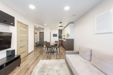 Samimi bir yaşam alanı, açık mutfak ve ahşap döşeme içeren modern ev tasarımı. Işıklar arasında zarif mobilyalar, nötr tonlar ve sıcak bir atmosfer yer alıyor.