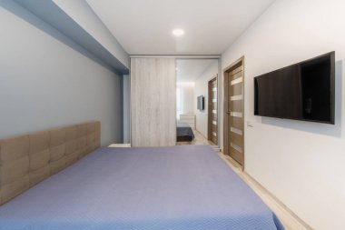 Parlak yatak odasının içinde modern bir tasarım, rahat bir yatak odası, televizyon ve şeffaf perdelerin arasından geçen doğal bir ışık var. Rahatlamak ve rahatlamak için ideal barışçıl ve minimalist bir düzen..