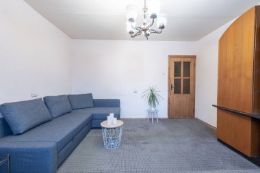 Modern mavi kanepesi, sehpası, ahşap mobilyası ve yumuşak ışıklandırması olan parlak ve rahat bir oturma odası. İçerisi basitlik ve işlevsellik yayar, rahatlama ve küçük toplantılar için mükemmeldir..