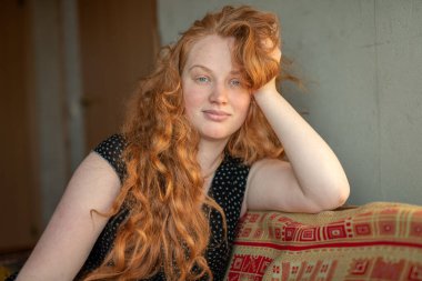 Kafkasyalı beyaz bir kadının sakin ve düşünceli bir portresi. Çekici kızıl saçlı, kızıl saçlı, evde oturan ve rahat oturan...,