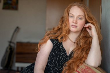 Kızıl saçlı, yeşil gözlü, özgünlük ve özgüven saçan, atmosferik ışıklandırma görüntüye sıcaklık ve karakter katan doğal ve anlamlı bir kadın portresi..