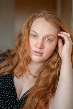 Kızıl saçlı, yeşil gözlü, özgünlük ve özgüven saçan, atmosferik ışıklandırma görüntüye sıcaklık ve karakter katan doğal ve anlamlı bir kadın portresi..