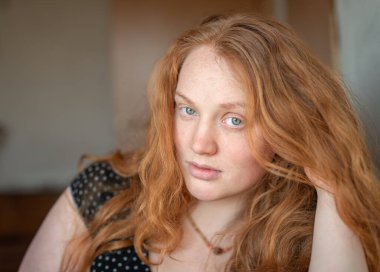 Kızıl saçlı, yeşil gözlü, özgünlük ve özgüven saçan, atmosferik ışıklandırma görüntüye sıcaklık ve karakter katan doğal ve anlamlı bir kadın portresi..