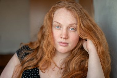 Kızıl saçlı, yeşil gözlü, özgünlük ve özgüven saçan, atmosferik ışıklandırma görüntüye sıcaklık ve karakter katan doğal ve anlamlı bir kadın portresi..