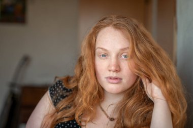 Kızıl saçlı, yeşil gözlü, özgünlük ve özgüven saçan, atmosferik ışıklandırma görüntüye sıcaklık ve karakter katan doğal ve anlamlı bir kadın portresi..