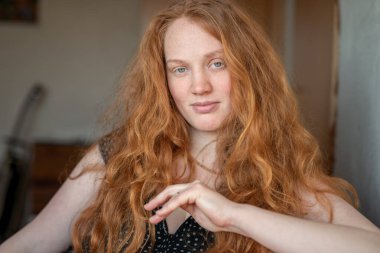 Kızıl saçlı, yeşil gözlü, özgünlük ve özgüven saçan, atmosferik ışıklandırma görüntüye sıcaklık ve karakter katan doğal ve anlamlı bir kadın portresi..