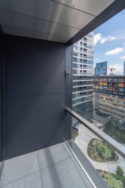 Yüksek binalar ve peyzaj alanları da dahil olmak üzere modern şehir mimarisine bakan yüksek katlı bir balkondan manzara