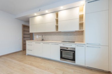 Çağdaş ev mutfağı. Parlak beyaz dolaplar, modern ev aletleri ve geniş tezgahlar.