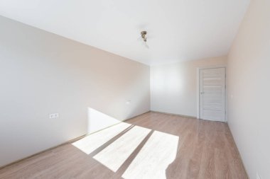 Minimalist, soluk duvarları, ahşap döşemeleri ve pencereden içeri giren doğal ışığı olan boş bir oda. Beyaz Duvar Odası Köşesi