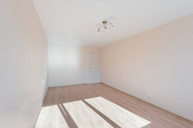 Minimalist, soluk duvarları, ahşap döşemeleri ve pencereden içeri giren doğal ışığı olan boş bir oda. Beyaz Duvar Odası Köşesi