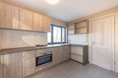 Parlak ve modern ev mutfağı. Ahşap dolaplar sergileniyor. Fayanslı döşeme, dahili cihazlar.