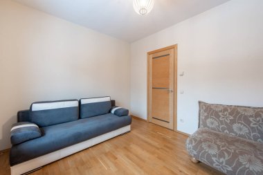 Çağdaş mobilyalar, ahşap döşemeler ve minimalist bir tasarımın yer aldığı parlak ve şık bir oturma odası. İç tasarım, ev dekorasyonu veya gayrimenkul listeleri için ideal.