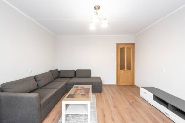 Gri bölmeli kanepesi, ahşap döşemesi ve zarif ışıklandırması olan, çağdaş minimalist bir tasarımın somutlaştırıldığı açık ve ferah bir oturma odası. Hafif tonlarda sadelik sakin bir karşılama ortamı sunar..