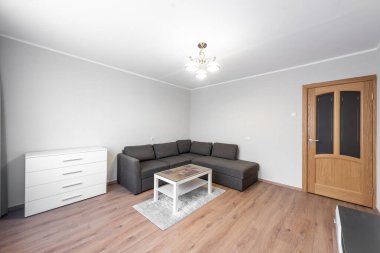 Gri bölmeli kanepesi, ahşap döşemesi ve zarif ışıklandırması olan, çağdaş minimalist bir tasarımın somutlaştırıldığı açık ve ferah bir oturma odası. Hafif tonlarda sadelik sakin bir karşılama ortamı sunar..