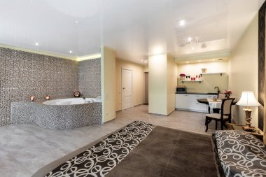 Bir yatak odası, fayanslı jakuzi alanı ve rahat mutfak düzeneği olan şık bir otel odası tasarımı. Geniş Otel Suitinde Yatak Odası, Jakuzi ve Mutfak ile Modern Ev İçi