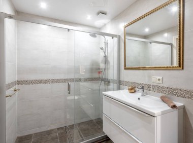 Temiz ve rahatlatıcı bir atmosfer için cam kaplı duş, beyaz gösteriş ve dekoratif aksanlı iyi tasarlanmış modern bir banyo. Modern Minimal Ev Banyosu Cam Duş Tarzı Detayları