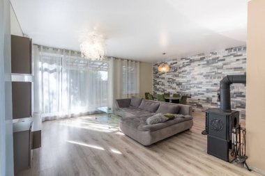 Geniş oturma odası geniş bir kanepe, doğal ışık ve rahat ahşap sobası olan çağdaş bir tasarım içeriyor..