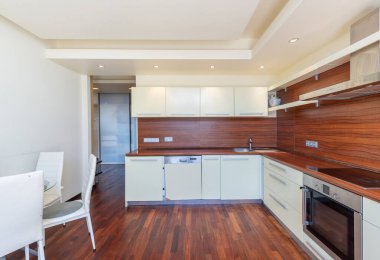 Beyaz dolaplar, ahşap döşemeler, modern aletler, temiz ve işlevsel bir çalışma alanı yaratan modern bir mutfak. Ahşap döşeme ve Beyaz Dolaplı Modern Ev Mutfağı