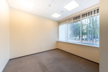 Geniş pencereleri ve temiz tasarımı olan parlak ve boş ofis içi, doğal ışıkla aydınlatılmış profesyonel bir çalışma alanı sunuyor. Geniş Pencereli İyi Aydınlatılmış Boş Oda İçi Temiz Tasarım