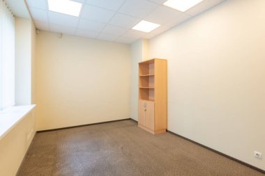Tek bir ahşap kitaplık ve nötr bej duvarlı minimalist boş bir ofis. Tahta bir kitaplığı ve bej duvarları olan Basit Boş Ofis Alanı.