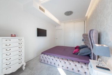 Zarif bir yatak odası, mor bir yatak odası, beyaz çekmeceler, ve minimalist dekorlar, rahatlık ve estetik için mükemmel bir stil..
