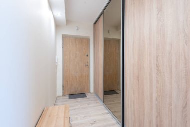 Parlak ve davetkar ev girişinde ahşap paneller, büyük bir ayna ve basit tasarım elementleri, çağdaş minimalizmi sergiliyor. Tahta Kapılı Modern Minimalist Giriş Ayna Aksanlı