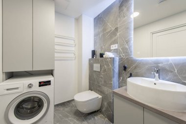 Parlak Modern Lüks Ev Banyosu Beyaz Lavabolu İç Tasarım. Mermer Duvarlar, Ayna ve Musluk. LED Ayna Işıkları. Isıtıcı. Duş, döşeme ve duvarlar. Güldürücü. Geniş Açı