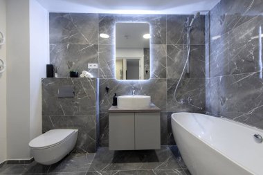 Parlak Modern Lüks Ev Banyosu Beyaz Lavabolu İç Tasarım. Mermer Duvarlar, Ayna ve Musluk. LED Ayna Işıkları. Banyo alanı, döşeme ve duvarlar. Geniş Açı