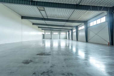 Boş Endüstri Deposu. Geniş, açık, parlayan beton zemin, çelik kirişler ve parlak ışıklandırma içeren bir sanayi deposu. Bu alan depolama, lojistik ve imalat için ideal..