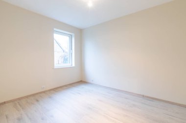 Ahşap döşemeleri ve geniş pencereleri olan boş bir odanın yeni, parlak ve modern iç mimarisi. Ev İçi