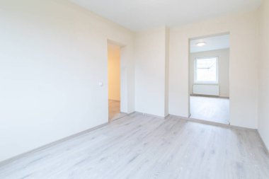 Ahşap kaplama döşeme, tarafsız duvarlar ve çağdaş bir titreşim ile iyi aydınlatılmış geniş bir oda. Ahşap döşemeleri olan parlak, modern boş oda. Yeni İnşaat İç mimarisi