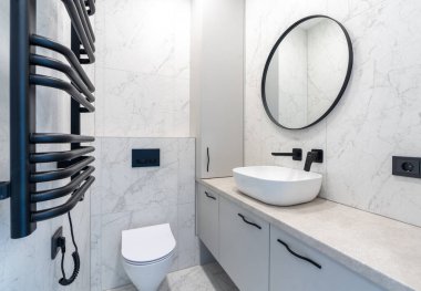 Minimalist banyo iç tasarımı mermer döşemeli duvar, yuvarlak ayna, leğen ve siyah armatürler içeriyor. Kullanışlı bir planı olan şık ve gösterişli bir yer. Ev İçi