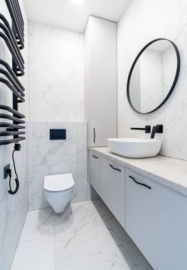 Minimalist banyo iç tasarımı mermer döşemeli duvar, yuvarlak ayna, leğen ve siyah armatürler içeriyor. Kullanışlı bir planı olan şık ve gösterişli bir yer. Ev İçi
