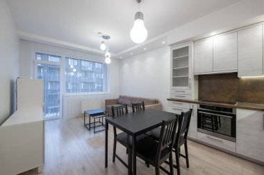 Rahat bir oturma alanı ve fonksiyonel bir mutfağı birleştiren geniş, çağdaş bir yaşam alanı. Tarafsız renklerle şekillendirilmiş, modern ışıklandırma. Modern Minimalist Ev Oturma Odası ve Mutfak İçi