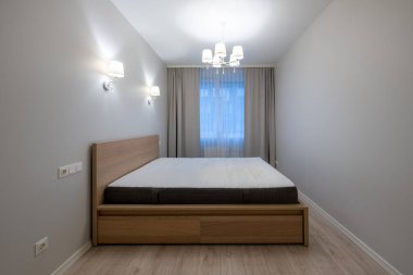Parlak ve temiz bir yatak odası, ahşap mobilyalar, modern ışıklandırma, büyük pencereler, doğal gün ışığı. Ev Minimalist Yatak Odası İçi. Arka planda Büyük Boyut Yatak, Pencereler ve Perdeler.