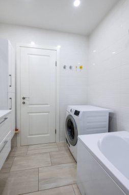 Döşemeleri döşemeli parlak çamaşır odası, çamaşır makinesi ve beyaz renkli modern iç dekorasyon. Temiz Çizgileri ve Tarafsız Renkleri Olan Minimalist Banyo