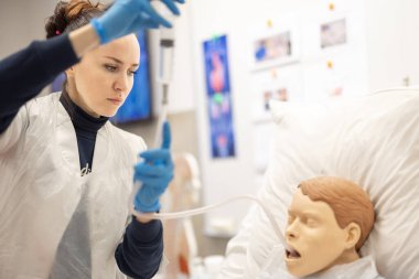 Sağlık çalışanı, profesyonel bir çevrede hasta bakımı teknikleri uygular, eğitim, hassasiyet ve sağlık eğitimini vurgular. Hemşire ile Tıbbi Simülasyon Eğitimi