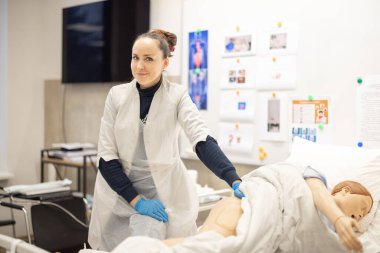 Eğitim ortamında tıbbi bir manken üzerinde hasta bakımı teknikleri uygulayan bir sağlık uzmanı. Görüntü, kontrollü ve eğitici bir ortamda öğretim ve öğrenme klinik becerilerini yansıtır.