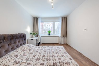 Tarafsız tonlarda dekore edilmiş rahat bir yatak odası, rahat bir yatak, büyük pencereler ve güneş ışığı. Taze bitkiler ve zarif mobilyalar. Modern Parlak Ev Yatak Odası İçi