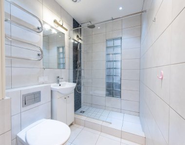 Parlak ve çağdaş banyo tasarımı. Duş, fayanslı duvarlar ve parlak paslanmaz çelik aksanlı beyaz seramik aksesuarlar. Modern Ev Banyosu İçi